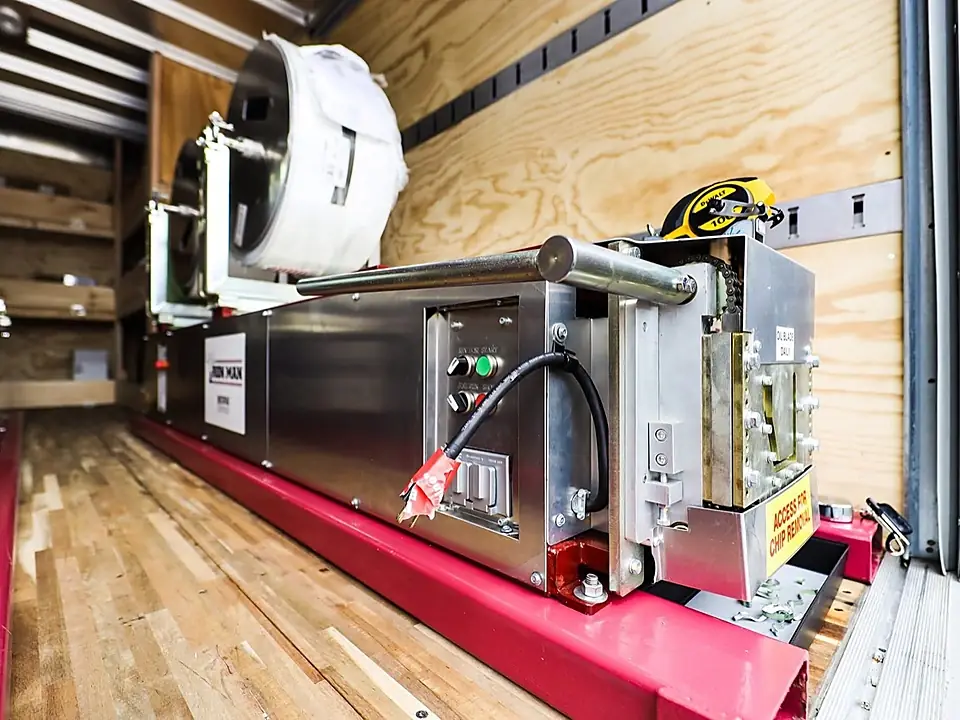 Close-up of Alpha Seamless Gutter machine controls and aluminum coil inside the truck